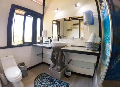 a bathroom with a sink and a toilet and a mirror at Coyote Rooms in Cabuya