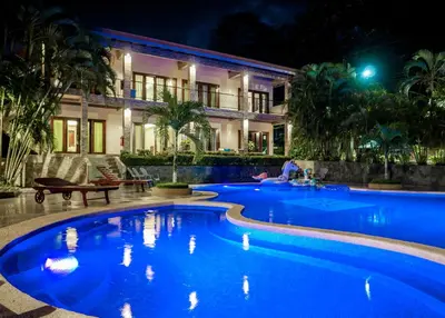 a swimming pool in front of a building at night at Hotel Amira in Carrillo