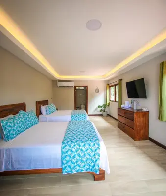 a bedroom with two beds and a flat screen tv at Hotel Amira in Carrillo
