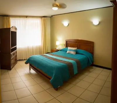 a bedroom with a bed with a blue comforter at Hotel y Restaurante El Guarco in Cartago