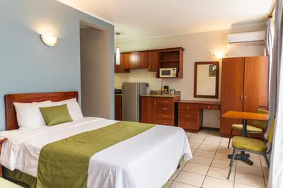 a hotel room with a bed and a kitchen at Hotel y Restaurante El Guarco in Cartago