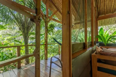 a room with a porch with a chair and trees at Private jungle “Loft del Rio” river access in Uvita