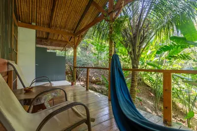 a hammock on the porch of a house at Private jungle “Loft del Rio” river access in Uvita