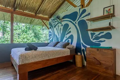 a bedroom with a bed with a blue painted wall at Private jungle “Loft del Rio” river access in Uvita
