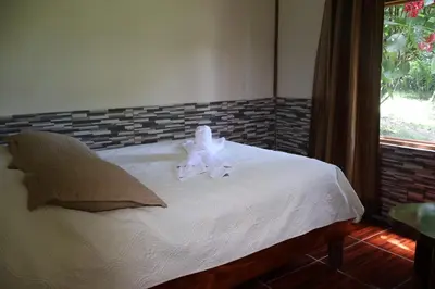 a bed with a white flower on top of it at Granja los Campesinos in Monteverde Costa Rica