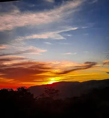 a sunset with the sun setting over the mountains at Granja los Campesinos in Monteverde Costa Rica