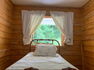 a bed in a wooden room with a window at La Cabaña Poas in Poás