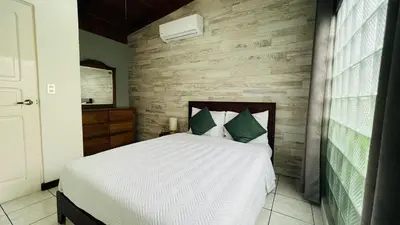 a bedroom with a white bed and a wooden wall at Stada San Jose Airport Hotel in Alajuela City