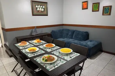 a table with plates of food on it with a couch at Stada San Jose Airport Hotel in Alajuela City