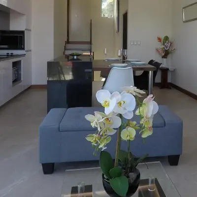 a living room with a blue couch and flowers in a vase at Cozy private Apartment, Mirador Escazú -Great view- in Escazu