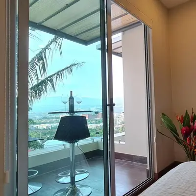 a bedroom with a view of the ocean from a window at Cozy private Apartment, Mirador Escazú -Great view- in Escazu