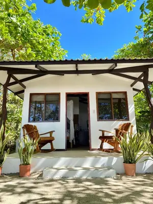 a small house with a porch and two chairs at Villas Paraiso Azul in Santa Teresa Beach