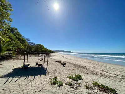 a beach with chairs on the sand and the ocean at Villas Paraiso Azul in Santa Teresa Beach