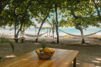 a basket of fruit on a wooden table with a beach at Villas Paraiso Azul in Santa Teresa Beach