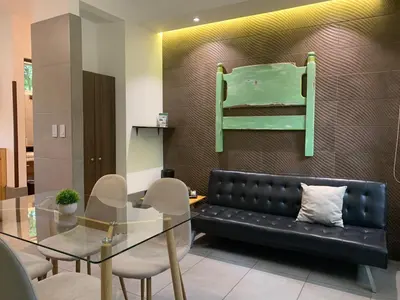 a living room with a black couch and a glass table at ARANJUEZ LOFTS Santa Ana in Santa Ana