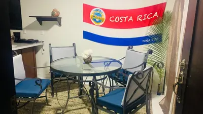 a glass table and chairs with a flag on a wall at Around Juan Santa María in Alajuela City