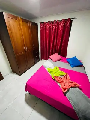 a bedroom with a pink bed and red curtains at Around Juan Santa María in Alajuela City
