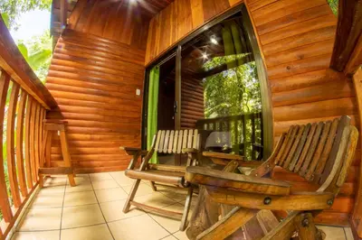 a porch with two rocking chairs and a window at Arenal Rústic Lodge in Fortuna