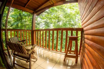 a porch with a rocking chair and a stool at Arenal Rústic Lodge in Fortuna