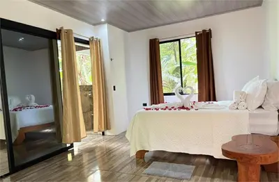 a bedroom with a bed with a table and a window at Arenal Rústic Lodge in Fortuna