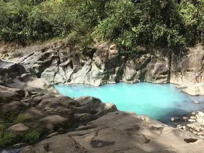 a blue pool of water on a rocky hillside at Tiny House Dreamcatcher in Sarchí Sur