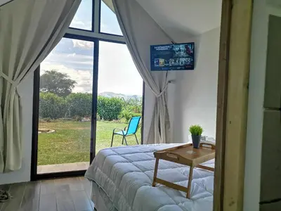 a bedroom with a bed and a table and a window at Tiny House Dreamcatcher in Sarchí Sur