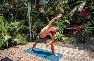 a man doing a handstand on a yoga mat at Akih Pods Hostel in Santa Teresa Beach