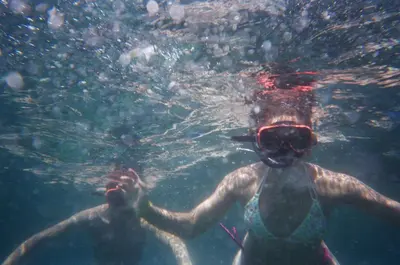 a woman in the water with a bear on her face at Akih Pods Hostel in Santa Teresa Beach