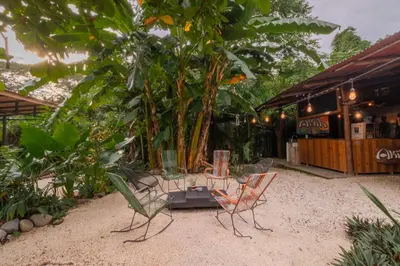 two chairs and a table in front of a building at Akih Pods Hostel in Santa Teresa Beach