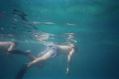 a person swimming in the water in the ocean at Akih Pods Hostel in Santa Teresa Beach