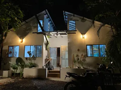 a house with lights on the side of it at Akih Pods Hostel in Santa Teresa Beach