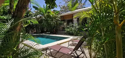 a swimming pool with two chairs and a house at Lapislazuli House & Flats with shared Pool in Santa Teresa Beach