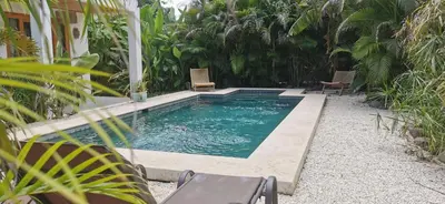 a swimming pool with two chairs in a yard at Lapislazuli House & Flats with shared Pool in Santa Teresa Beach