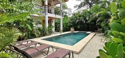 a swimming pool with two chairs and a house at Lapislazuli House & Flats with shared Pool in Santa Teresa Beach