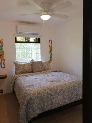 a bedroom with a bed with a ceiling fan at La Sirena Playa Jacó in Jacó
