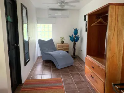 a living room with a blue chair and a dresser at La Sirena Playa Jacó in Jacó