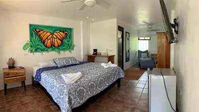 a bedroom with a bed with a butterfly painting on the wall at La Sirena Playa Jacó in Jacó