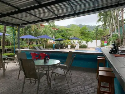 a patio with a table and chairs and a pool at La Sirena Playa Jacó in Jacó