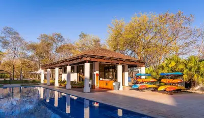 a pavilion with chairs and umbrellas next to a swimming pool at Bright 2BR Condo with Partial Ocean View - Bougainvillea - Reserva Conchal in Playa Conchal