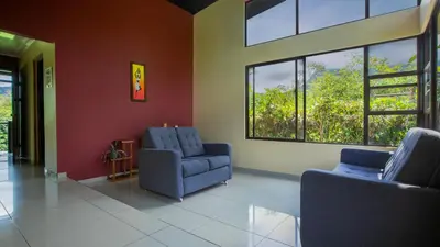 a living room with two blue chairs and windows at Green Leaf House in Fortuna