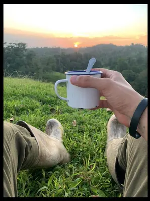 a person holding a cup of coffee in a field at El Zota Hotel in Cariari