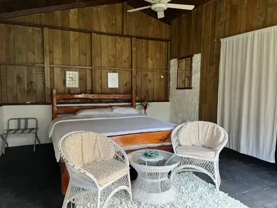 a bedroom with a bed with two chairs and a table at El Zota Hotel in Cariari