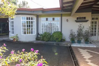 a house with a pool in the front yard at Hostel Bouganvilia Bed and Breakfast in San Ramón