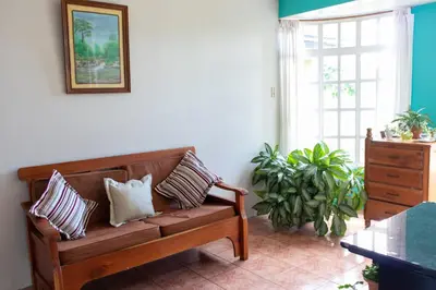 a living room with a wooden bench with pillows at Hostel Bouganvilia Bed and Breakfast in San Ramón