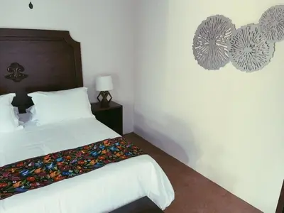 a bedroom with a white bed with a wooden headboard at Hacienda Escondida 10min to Airport in Alajuela City
