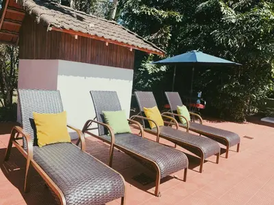 a row of chairs and an umbrella on a patio at Hacienda Escondida 10min to Airport in Alajuela City