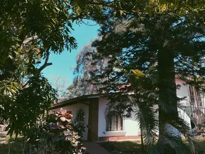 a white house with trees in front of it at Hacienda Escondida 10min to Airport in Alajuela City