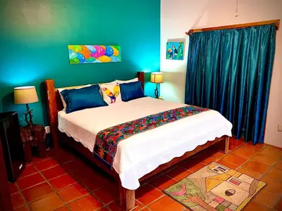 a bedroom with a bed with blue walls and blue curtains at Toucan Lane in Nuevo Arenal