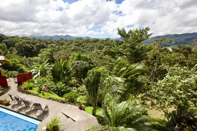 a resort with a swimming pool and mountains in the background at Toucan Lane in Nuevo Arenal
