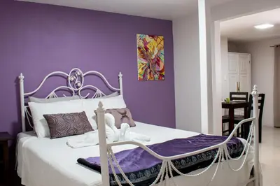 a bedroom with a white bed with a purple wall at Toucan Lane in Nuevo Arenal